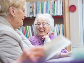 Older lady inside the library, laughing with a friend