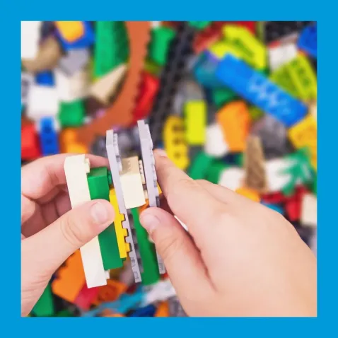 A photo of a child's hands sticking LEGO bricks together