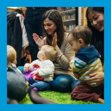 A photo of parents with babies in their laps clapping and smiling
