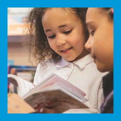 A photo of two girls enjoying a book together.