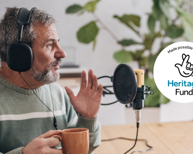 Older man holding hot drink and talking into a microphone for a podcast