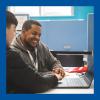 Two people smiling as they look at a laptop.