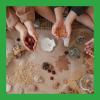 A photo of different leaves, seeds, and rocks arranged on a brown paper surface, with children's hands interacting with the different natural items.